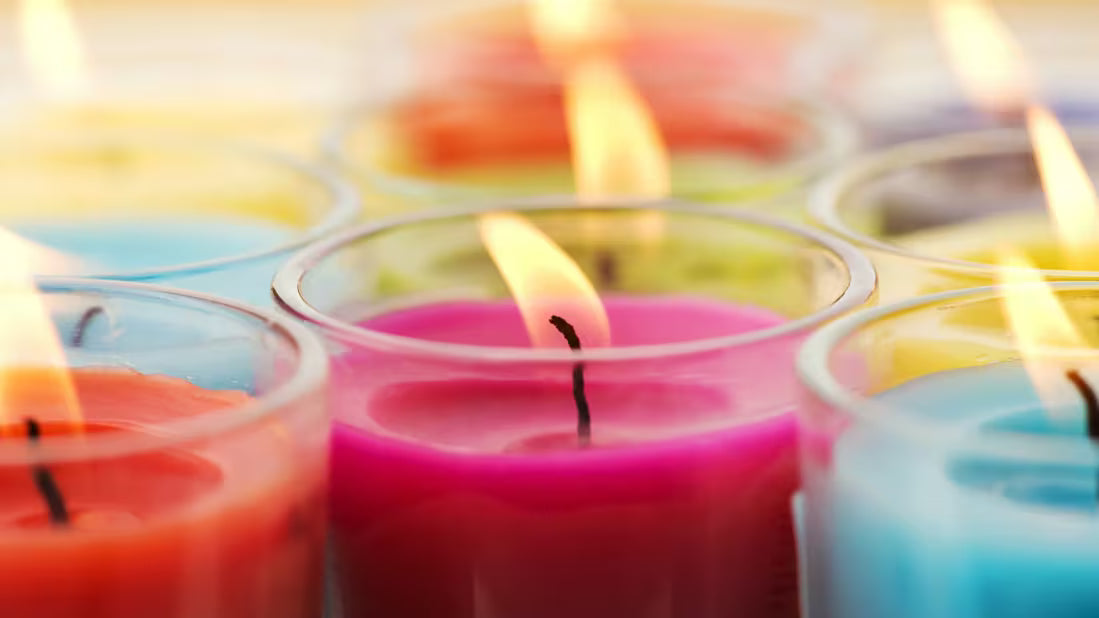 Colorful candles with flames, showing dyed wax and multiple wicks often found in low-quality candles